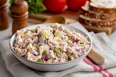 Bowl of Tuna Fish, a food high in taurine,  make into a salad. in a bowl, bread and salt and pepper shakers in the background