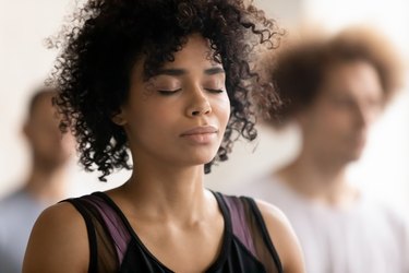 Young peaceful african american woman enjoying deep meditation.