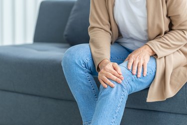 woman with knee pain on couch