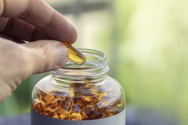 Person taking a fish oil capsule, as a natural remedy for anxiety