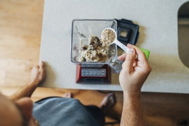 Overhead image of person pouring creatine powder into a blender to make a smoothie