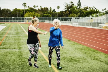 two older adults high fiving after workout on track exercising after gallbladder removal