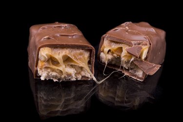 two slices of Snickers bars on a black background macro