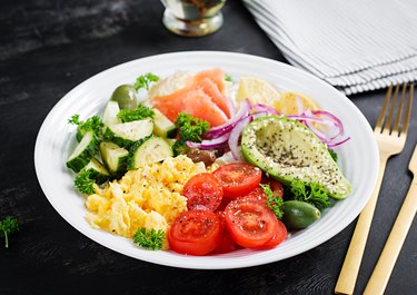 Avocado breakfast bowl with salmon, tomatoes, cucumbers, scrambled eggs and avocado.