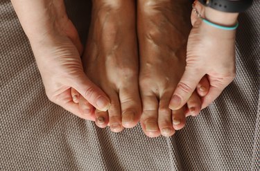 A close up of a person's hands and feet with their hands holding their toes
