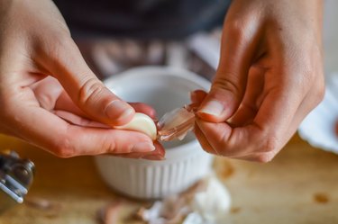 close view of hands peeling garlic, as a toothache remedy