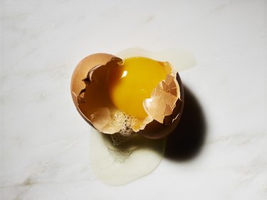 Broken egg in shell on white marble background
