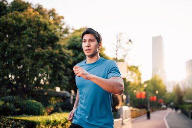 close-up of a man outside in a city park running with relaxed face muscles