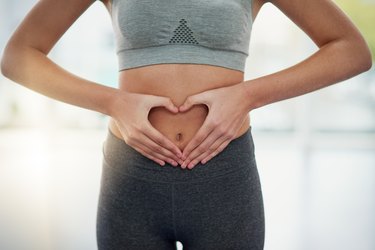 view of a person's midsection, with hands in a heart shape around the bellybutton to illustrate good gut health