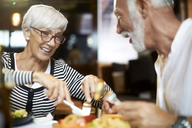 Older couple sharing food while dining together in a restaurant