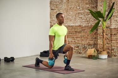 man doing kettlebell lunges on a purple exercise mat at home