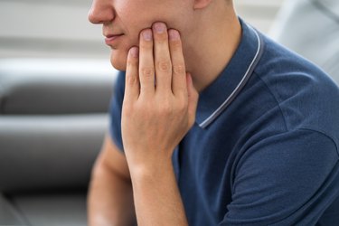 A man holding his jaw because of wisdom tooth pain