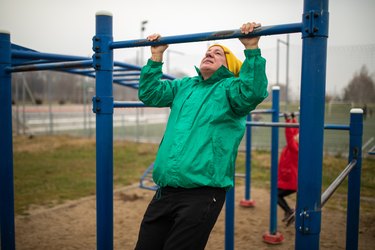 Older adult doing a pull-up outside in a park.