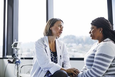 Smiling doctor talking to young woman with vertigo in the hospital