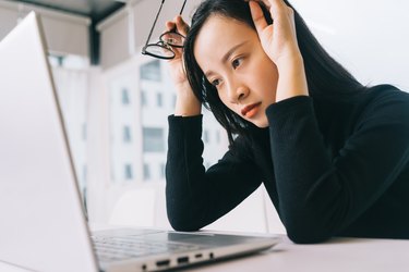 Asian businesswoman looking tired in front of a laptop,