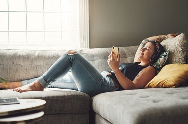 a woman laying on the couch and using a meditation app, as a tinnitus remedy