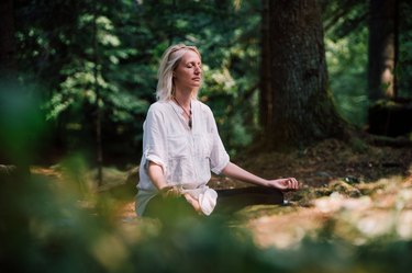 older woman sitting outside and doing breathing exercises to increase her lung capacity