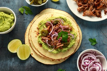overhead photo of corn tortilla with shredded Pork carnitas avocado, red onion and jalapeno flavored with bouillon cube
