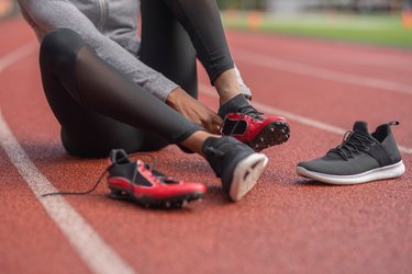 Athlete changes into red track spikes on a stadium field