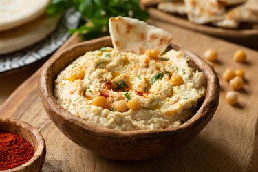 Homemade chickpea hummus bowl with pita chips and paprika