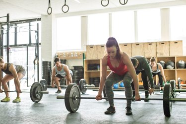 athletes doing barbell deadlift in group fitness class to illustrate concept of women's vs. men's lower-body strength