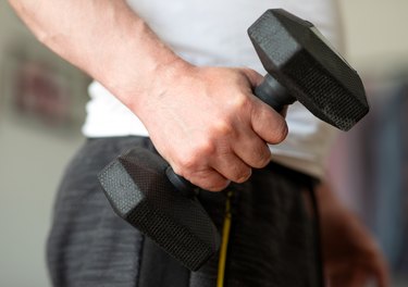 特写镜头的男人的手拿着哑铃做hand-strengthening练习