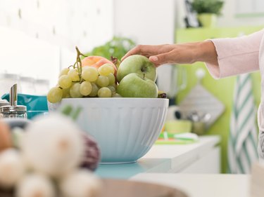 Woman taking an apple from a fruit bowl