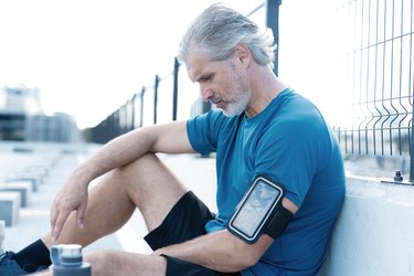 Tired Exhausted Middle-aged Man Resting After Running Outdoors. Handsome Runner Taking Break After Fitness Workout