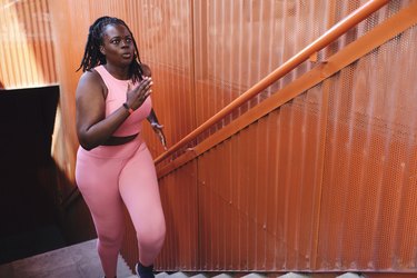 person in pink workout attire running up staircase to demonstrate best exercises for heart health