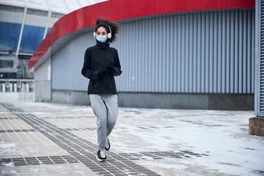 Sportive female in a mask jogging outside