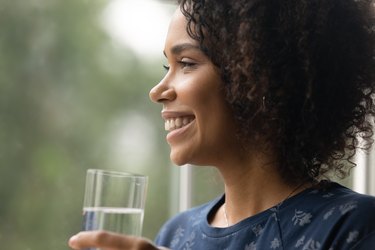 Close up smiling African American woman holding glass of water