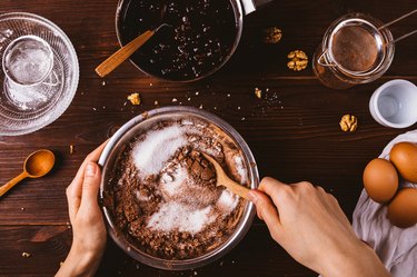 Top view female hands mix cocoa powder and looking for a nut substitute for cookie recipe