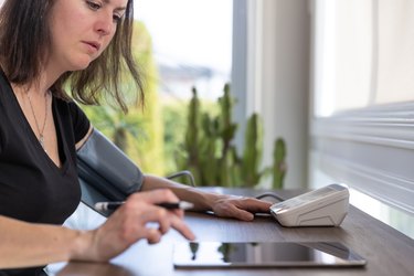 Adult Woman checking blood pressure on Auto blood pressure Machine at home