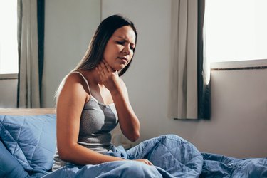 woman in bed waking up with a sore throat