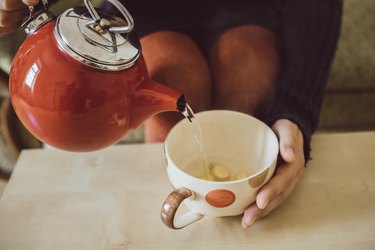 Woman pouring a cup of ginger tea, as a way to get rid of period cramps