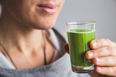 person holding shot of wheatgrass juice made from powdered wheatgrass