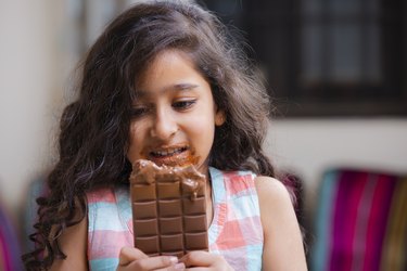 Girl with chocolate diarrhea allergy eating a bar of milk chocolate