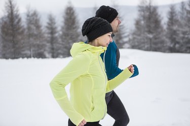 Couple running in cold weather during winter with snow on the ground