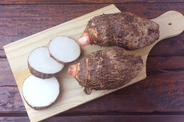 raw yam over rustic wooden table. Also known as Alocasia, Colocasia, Xanthosoma