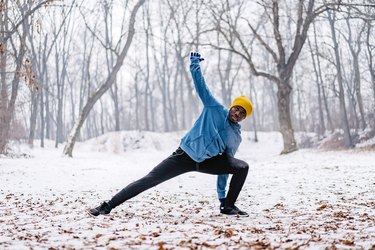Young Black person stretching in the snow.