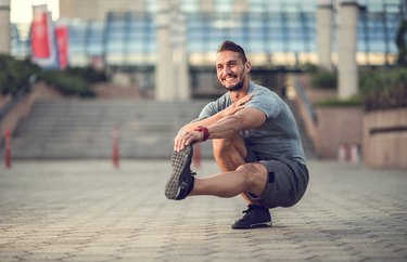 Happy athletic man doing a single-leg squat outside