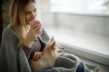 person drinking tea at home with dog for diverticulitis