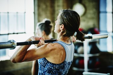Mature person going through menopause doing barbell lifts during workout at the gym