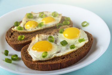 Home cooking. Whole grains Bruschettas with Fried Quail Eggs with green onions on plate.