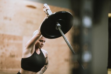 fit woman doing a single-arm landmine press shoulder exercise