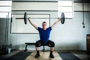 Man doing Olympic weight lifting in the gym; lifting barbell overhead; overhead squat