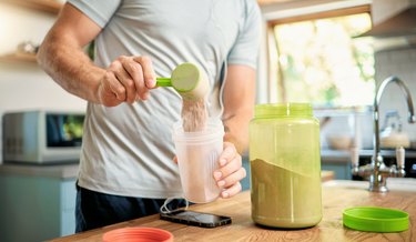 Closeup of a person making a protein shake with protein powder