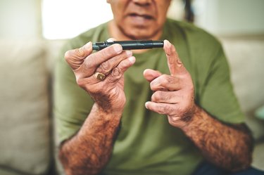 Shot of an older adult using a finger pricking device to check his blood sugar levels