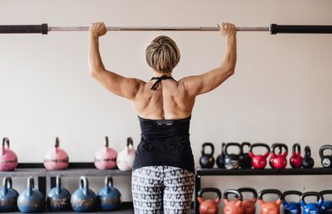 Mature woman training with fitness bar in a gym