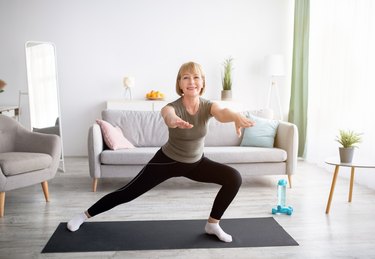 senior woman doing lunges at home in her living room